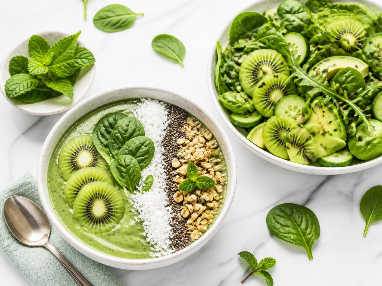 Taça de smoothie verde e salada fresca sobre mesa branca